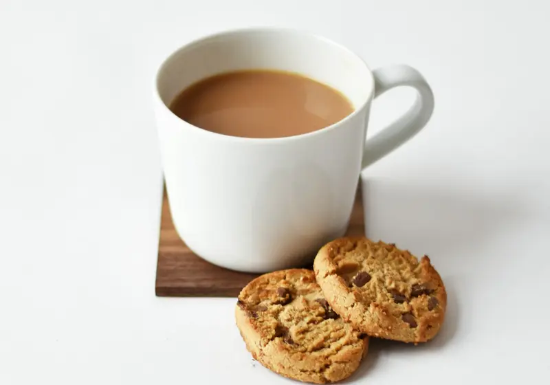 Cup of tea with two cookies on a wooden coaster